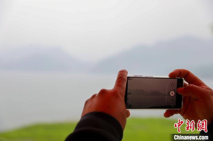 图为黄树鹏在用手机拍摄美景。　于海洋 摄